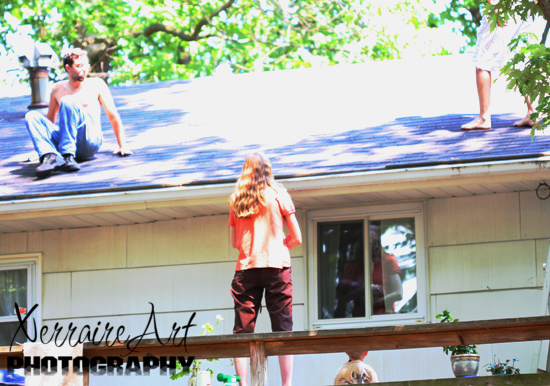 Miranda, atop the picnic table, babe in arms, watching Enric and Miquel on the roof.