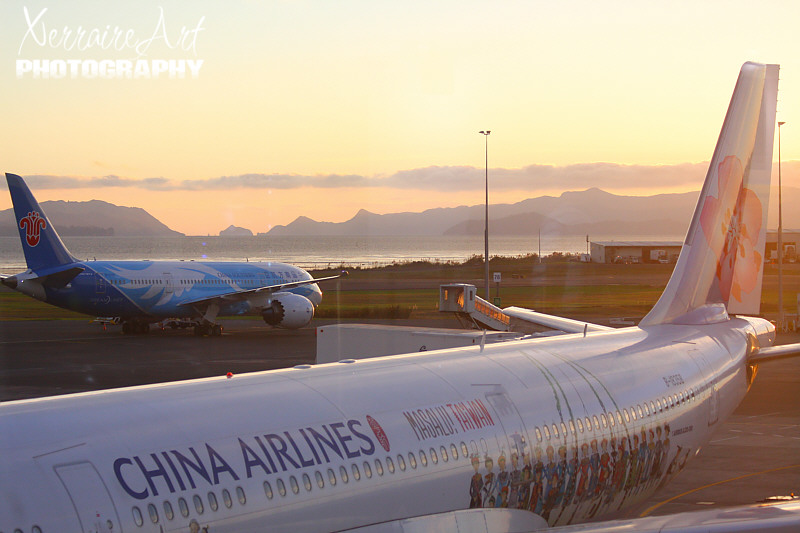 When I had talked to John and informed my family I was safe, the time had passed and it was getting late enough to be ready to look for the gate for the plane. But first a stop for the usual New Zealand sunset. I chose this place to take a photo as I like the China Airlines plane with the cute Chinese people pictured on the sides.