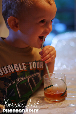 Blowing bubbles into the iced tea with a straw